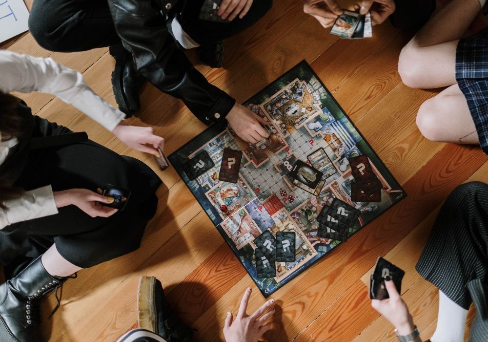 数人の友達とゲームを囲んでボードゲームをしている